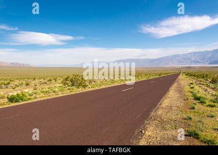 Trona Wildrose Straße, die zum Death Valley in Kalifornien an einem schönen sonnigen Tag mit blauem Himmel und die Berge als Hintergrund führt. Stockfoto