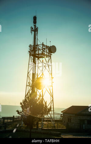 Silhouette von Telekommunikationsturm mit Antennen und Sun flare Effekt auf Sonnenuntergang in Guarda. Das gut erhaltene mittelalterliche Stadt in der östlichen Portugal. Stockfoto