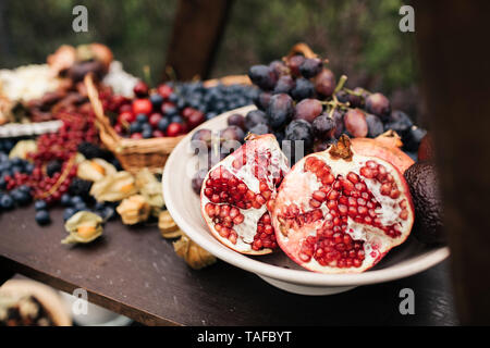 Granatapfel und Trauben in eine Platte auf dem Holztisch Stockfoto