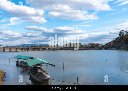 Boot an Hozu-gawa Fluss und Togetsu-kyo Brücke mit bunten Wald Berg Hintergrund in Arashiyama, Kyoto, Japan. Arashiyama ist ein National Desig Stockfoto