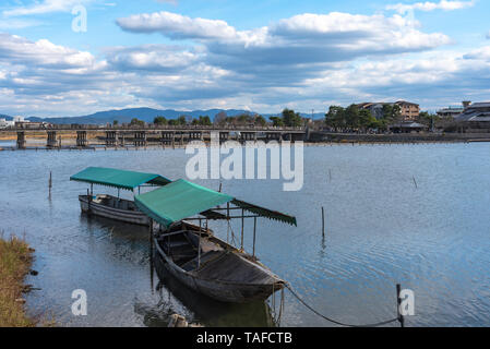 Boot an Hozu-gawa Fluss und Togetsu-kyo Brücke mit bunten Wald Berg Hintergrund in Arashiyama, Kyoto, Japan. Arashiyama ist ein National Desig Stockfoto