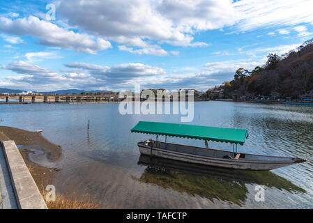 Boot an Hozu-gawa Fluss und Togetsu-kyo Brücke mit bunten Wald Berg Hintergrund in Arashiyama, Kyoto, Japan. Arashiyama ist ein National Desig Stockfoto