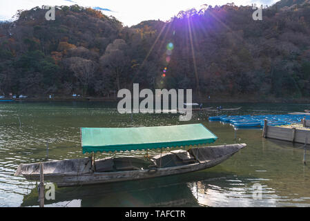 Boot an Hozu-gawa Fluss und Togetsu-kyo Brücke mit bunten Wald Berg Hintergrund in Arashiyama, Kyoto, Japan. Arashiyama ist ein National Desig Stockfoto