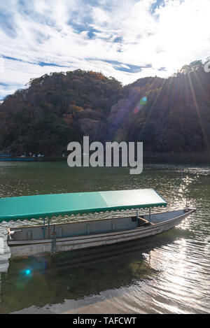 Boot an Hozu-gawa Fluss und Togetsu-kyo Brücke mit bunten Wald Berg Hintergrund in Arashiyama, Kyoto, Japan. Arashiyama ist ein National Desig Stockfoto