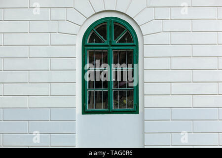 Grüne Bogenfenster auf ein sauberes, weißes Ziegelgebäude Stockfoto
