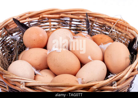 Einen Weidenkorb voll von hausgemachten Bio Eier auf weißem Hintergrund. Stockfoto