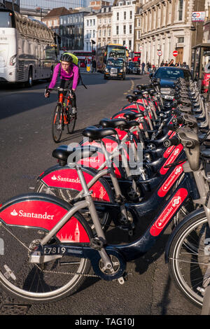 London Radfahrer TFL Santander gesponsert roten Londoner Fahrradverleih Fahrräder in Southwark Street. Pendler Radfahrer mit Helm Reiten am Fahrrad terminal Docking Station mit Verkehr hinter sich. Transport for London Southwark London UK Stockfoto