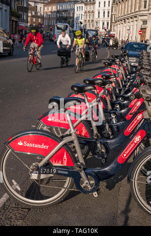 LONDON BIKES PENDLER TFL Santander sponsert London Red Leihbikes in der Southwark Street. Gruppe von Pendlerfahrern mit Helmen, die an der Andockstation des Fahrradterminals vorbeifahren. Transport nach London Southwark London UK Stockfoto