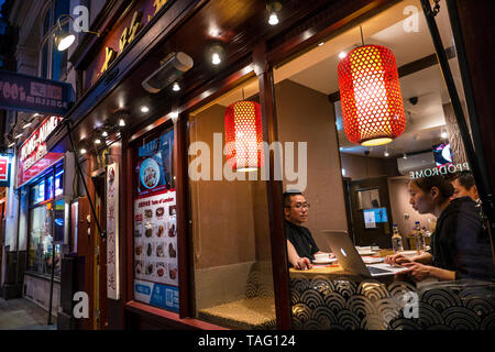 Orientalische Gruppe von vier zwischen 25 und 35 Jahren in ein Chinatown chinesische Restaurant an einem Tisch, Überprüfung der Bildschirm Informationen über ein Apple MacBook Computer Soho Chinatown West End London UK sitzen Stockfoto