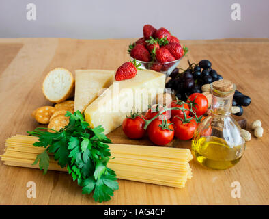 Spaghetti und Pasta auf dem hölzernen Hintergrund. Das Konzept des Kochens. Pasta, Tomaten, Käse, Minze und Erdbeeren. Für text Stockfoto