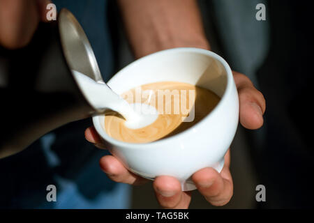 Americano oder Espresso latte, gießen Sie Milch. Barista gießen Sie Milch im Kaffee trinken. Die Ausgaben viel Zeit zu Hause. im Cafe oder kaufen und trinken entspannen. Perfekte mo Stockfoto