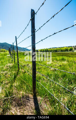 In der Nähe von Stacheldraht zaun & Holzzaun Beiträge gegen den klaren blauen Himmel; Ranch in Colorado, USA Stockfoto