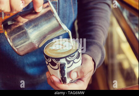 Der professionelle Barista gießt Latte Foam Tulpe über Kaffee, Espresso und schafft einen perfekten Cappuccino. Stock Foto Stockfoto