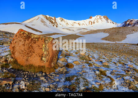 Ein großer Boulder in defocus auf der malerischen Pfad auf den Gipfel des Mount Erciyes an einem klaren sonnigen Tag vor blauem Himmel in Zentralanatolien, Turk Stockfoto