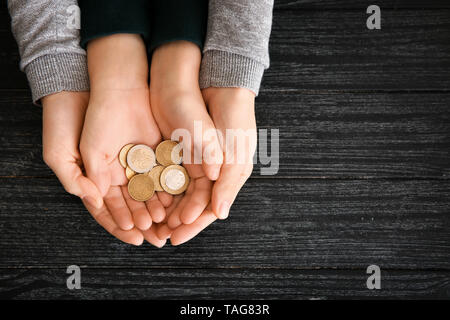 Die Hände der Frau und sein Sohn holding Münzen auf Holztisch. Konzept der Child Support Stockfoto