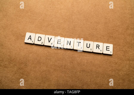 LONDON, UK, 24. Mai 2019: Das Wort Abenteuer, Dinkel mit hölzernen Buchstabensteine über eine braune strukturierten Hintergrund Stockfoto