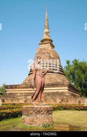 Skulptur eines walking Buddha vor dem Hintergrund eines mittelalterlichen Stupa. Ruinen von einem buddhistischen Tempel im historischen Park von der Sukhothai sity. Thail Stockfoto