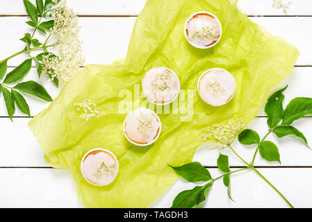 Hausgemachte Holunder blossom Muffins mit Zuckerguss und frische Holunderblüten. Flach. Stockfoto