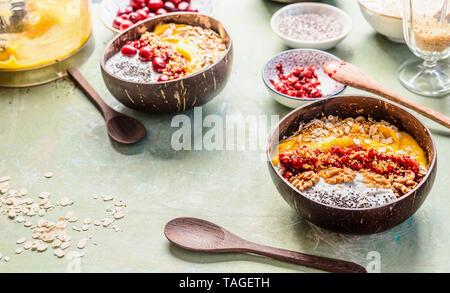 Frühstück smoothie Schüssel in Kokosnussschalen, gekrönt mit Haferflocken und Beeren und Nüsse. Sommer gesunde Ernährung, Veganes Frühstück. Stockfoto