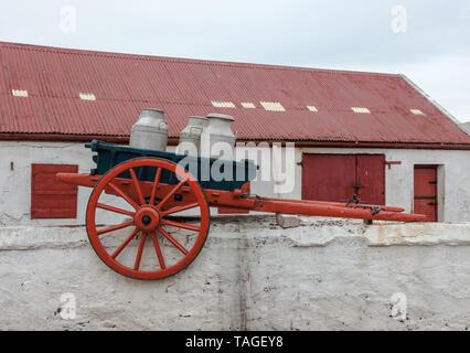 Knockadoon, Cork, Irland. Ein vintage Warenkorb mit Milchkannen, die jetzt als Dekoration benutzt worden ist, sitzt auf einer Farm in der Nähe von Mauer Knockadoon, Co Cork, Irela Stockfoto