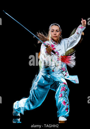 Eine chinesische Frau partacticing Tai Chi Chuan Tadjiquan Körperhaltung studio Schuß auf schwarzen Hintergrund mit Licht malen Effekt isoliert Stockfoto