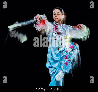 Eine chinesische Frau partacticing Tai Chi Chuan Tadjiquan Körperhaltung studio Schuß auf schwarzen Hintergrund mit Licht malen Effekt isoliert Stockfoto