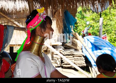 LONGNECK KAREN DORF, THAILAND - Dezember 17. 2017: Im Alter von alten langen Hals Frau vor einem Bambus Hütte mit Strohdach sitzen Stockfoto