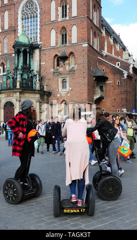 Junge Leute auf Segways treffen in Krakau Old City Square, Rynek Glowny, vor der St. Mary's Basilica. Stockfoto