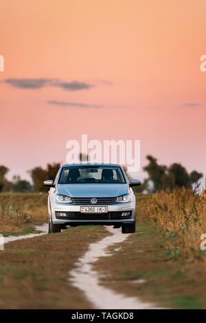 Gomel, Weißrussland - 14. September 2016: Volkswagen Polo Vento Limousine Parkplatz in der Nähe von Landstraße im Herbst Feld. Sonnenuntergang Sonnenaufgang Himmel auf einem Hintergrund In Stockfoto