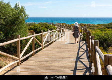 Frau zu Fuß entlang der Promenade durch die erhaltenen natürlichen Küstenregion am Playa Artola, Cabopino, Costa del Sol, Spanien Stockfoto