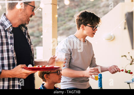 Familie Mittags gemeinsam im Freien zu Hause - Leute genießen Freizeit Essen-kaukasischen Erwachsene und Kinder und Jugendliche für drei generiert Stockfoto
