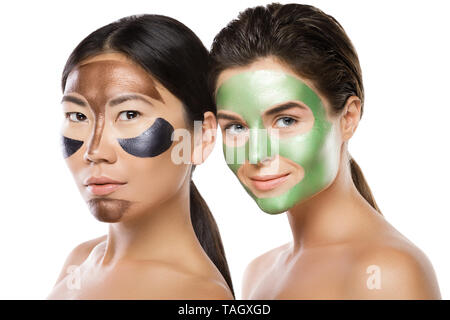 Zwei schöne Mädchen mit bunten Peel-off Maske auf ihren Gesichtern. Auf weissem Hintergrund Stockfoto