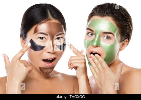 Zwei schöne Mädchen mit bunten Peel-off Maske auf ihren Gesichtern. Auf weissem Hintergrund Stockfoto