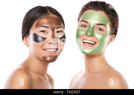 Zwei schöne Mädchen mit bunten Peel-off Maske auf ihren Gesichtern. Auf weissem Hintergrund Stockfoto