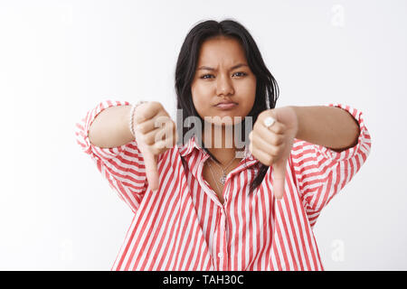 Nicht cool. Portrait von unzufrieden und enttäuscht Junge düstere umgekippt Frau unzufrieden von schlechten Verhalten zeigen Daumen unten Schmollen und Stockfoto