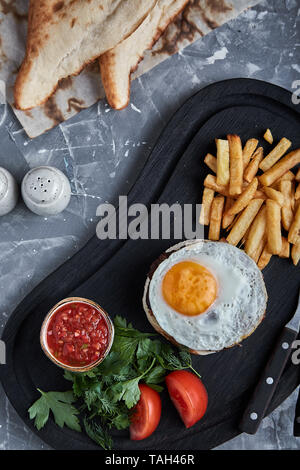 Rindersteak mit Ei und Salat aus grünen und Gemüse. Grauer Hintergrund, Tisch, Fine Dining Stockfoto