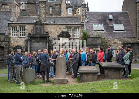 Touristen auf einem Spaziergang durch Edinburgh besuchen das Grab von John Gray, dem Meister von Greyfriars Bobby, in Greyfriars Kirkyard. Stockfoto