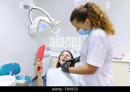 Prozess der zahnmedizinischen Behandlung. Weibliche Patienten wählt Farbe der Zähne von zwei vom Arzt Zahnarzt ausgewählt. Gesundheit, Medizin und Zahnmedizin Konzept Stockfoto