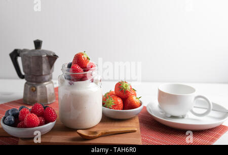 Joghurt mit Erdbeeren, Himbeeren und Heidelbeeren auf dem Frühstückstisch. Stockfoto