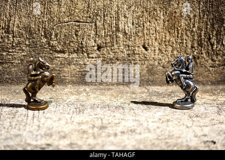 Zwei bronzene Schachfiguren Ritter einander gegenüber im Fokus und Defokussierten Stockfoto