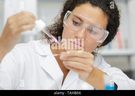 Wissenschaftlerin Hinzufügen flüssiger Rohr mit Pipette zu testen Stockfoto