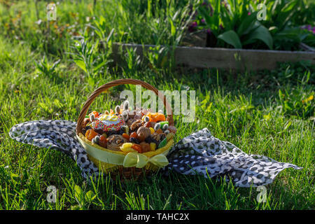 Korb mit Ostern Kuchen, getrocknete Früchte und Nüsse auf dem grünen Gras im Garten Stockfoto