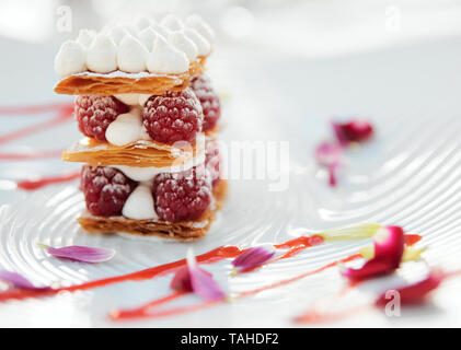 Scheibe der Mille-feuille Torte mit Himbeeren und süßen Soße auf Porzellan Platte Stockfoto