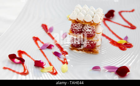 Scheibe der Mille-feuille Torte mit Himbeeren und süßen Soße auf Porzellan Platte Stockfoto