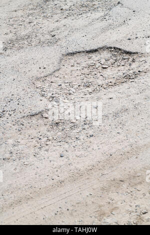 Schlagloch in einem Parkplatz am Meer. Konzept Unebener Untergrund, schlechte Wartung, kaputte Infrastruktur, schlechter Job, raue Straße voraus. Stockfoto