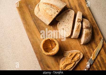 Frisches Brot mit Erdnussbutter auf Holzbrett Stockfoto