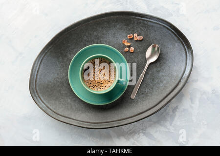 Eine Tasse schwarzen Kaffee, geschossen von oben auf ein Fach mit karamellisierten Zucker, einem Löffel und einem Platz für Text Stockfoto