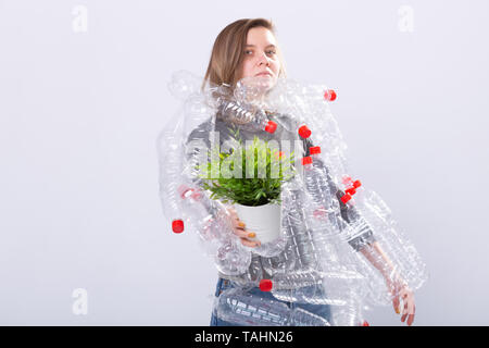 Kunststoff Problem der Umweltverschmutzung und Umweltschutz. Müde Frau mit Plastikflaschen Holding grüne Pflanze schwach. Speichern der Erde. Reinigen unserer Natur. Stockfoto