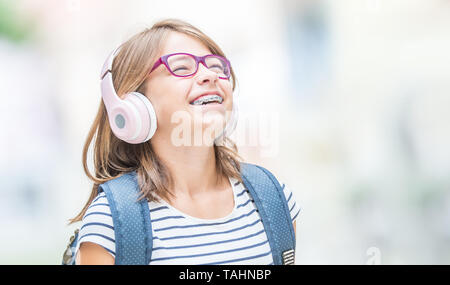 Glücklich lächelnde Schulmädchen mit Zahnspangen und Gläser Musik über die Kopfhörer. Kieferorthopäde und Zahnarzt Konzept. Stockfoto