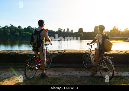 Touristische paar Radfahren im Tempel Angkor, Kambodscha. Angkor Wat Hauptfassade auf Wasser Teich wider. Umweltfreundliche Tourismus reisen. Stockfoto